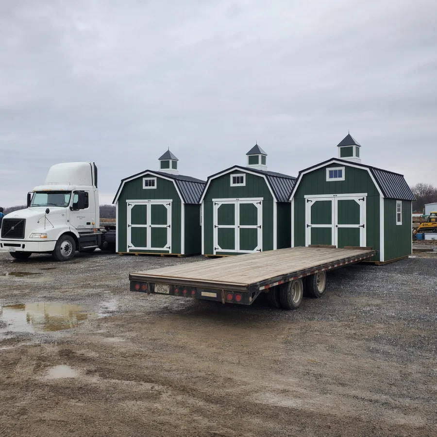 Cupola-topped buildings staged beside a delivery truck and flatbed trailer
